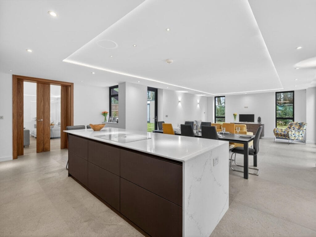 Luxury open-plan kitchen and dining area with large island, contemporary lighting and spacious entertaining layout.