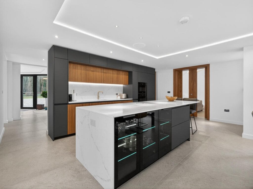 Luxury modern kitchen with large marble island, integrated appliances, handleless cabinetry and open-plan layout.