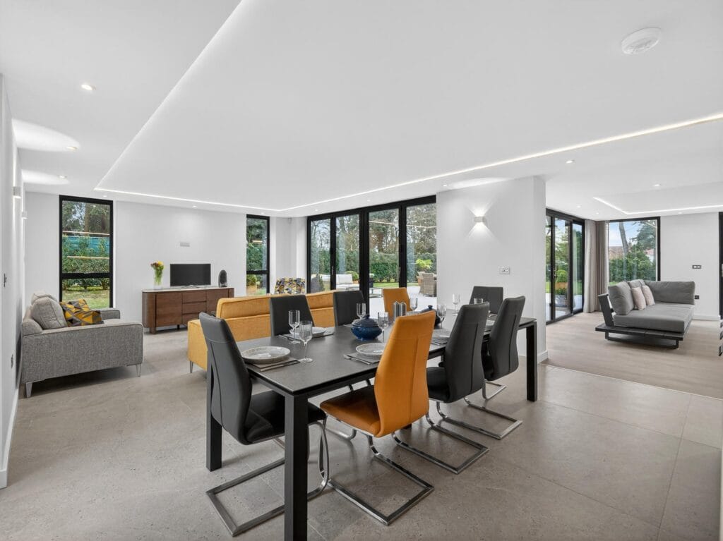 Spacious open-plan living and dining area with contemporary furniture, large sliding doors and garden views.