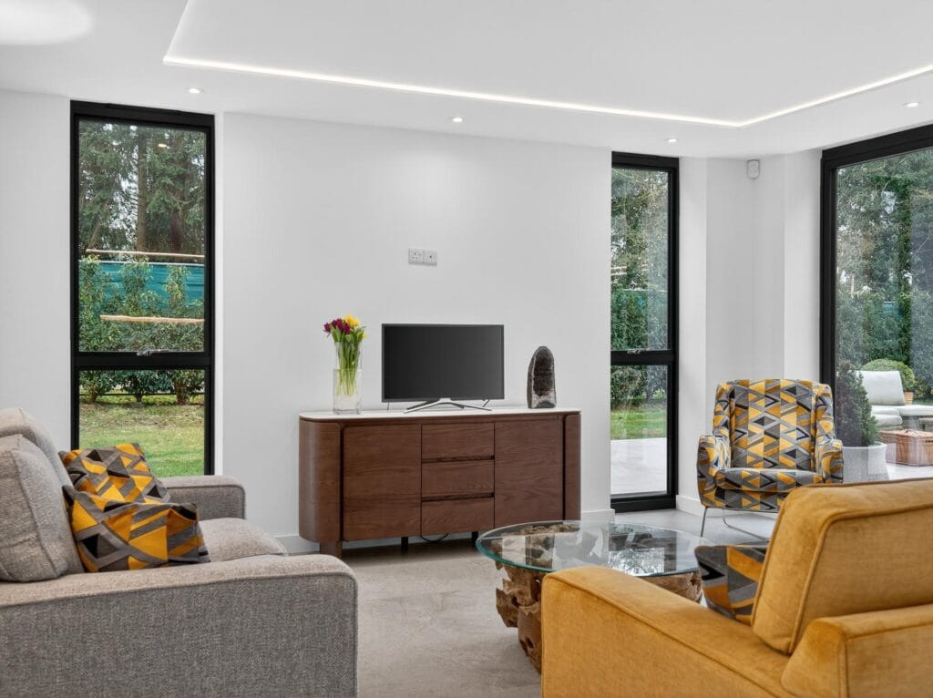 Contemporary family living area with modern seating, large windows and views to the garden and patio.