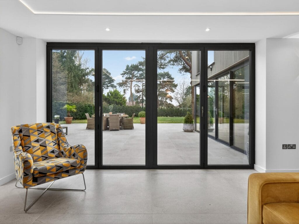 Family room with large sliding glass doors opening onto a modern patio and landscaped garden seating area.