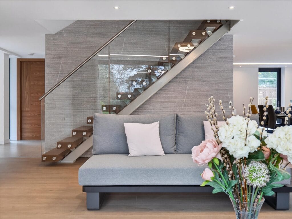 Contemporary floating staircase with glass balustrade in a modern open-plan living space.