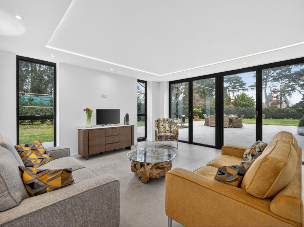 Modern family living room with floor-to-ceiling sliding doors opening to a patio and landscaped garden.