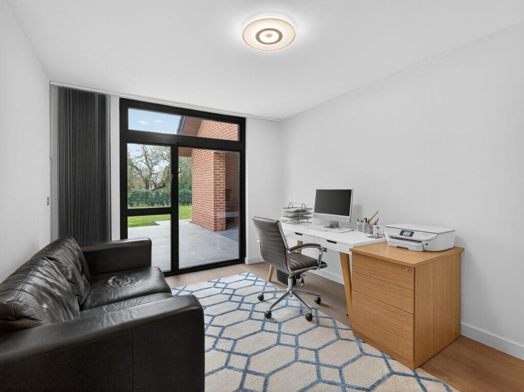 Modern home office with desk workspace, natural light and door opening to the garden patio.