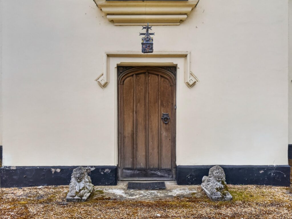 Arched oak front door of The Priory Suffolk with carved stone surround and antique lantern above