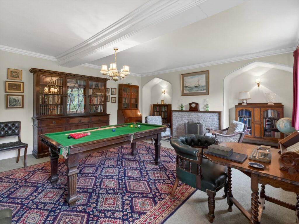 Library and snooker room at The Priory Suffolk shown from the opposite end with ceiling beams and Gothic alcoves