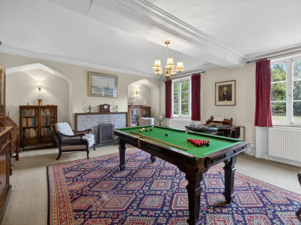 Library and snooker room at The Priory Suffolk with Gothic arched alcoves, brick fireplace and ceiling beams