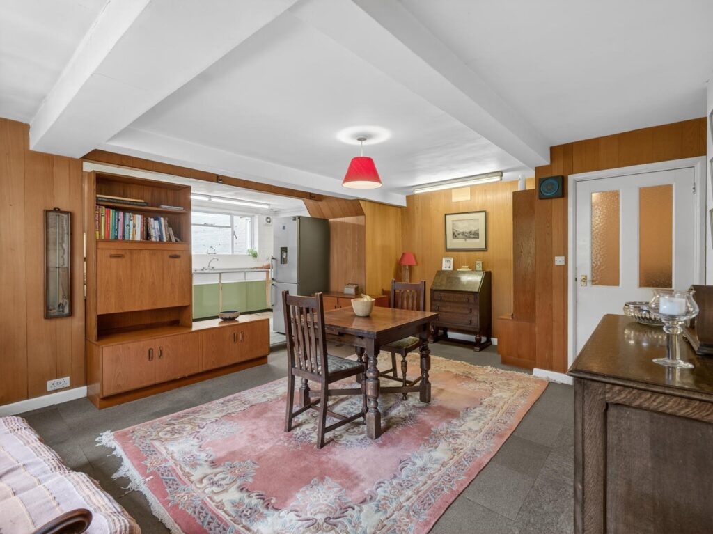 Breakfast room at The Priory Suffolk with exposed ceiling beams, timber panelling and open access to the kitchen