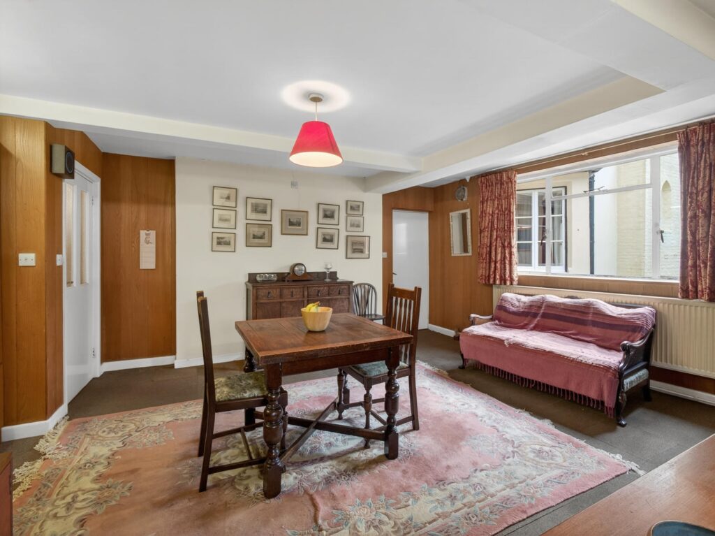 Breakfast room at The Priory Suffolk shown from the kitchen with timber panelling, ceiling beam and window onto courtyard