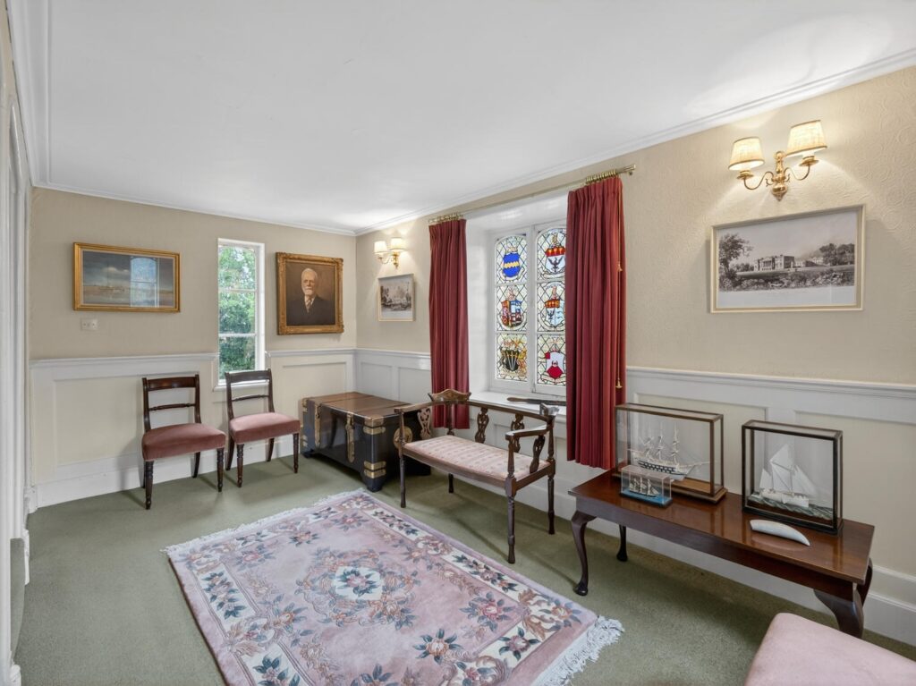 Upstairs landing at The Priory Suffolk with half-height wall panelling and heraldic stained glass window