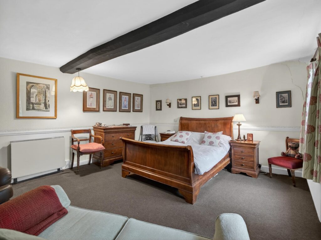 Beamed bedroom at The Priory Suffolk shown from the opposite end with substantial blackened ceiling beam and dado rail