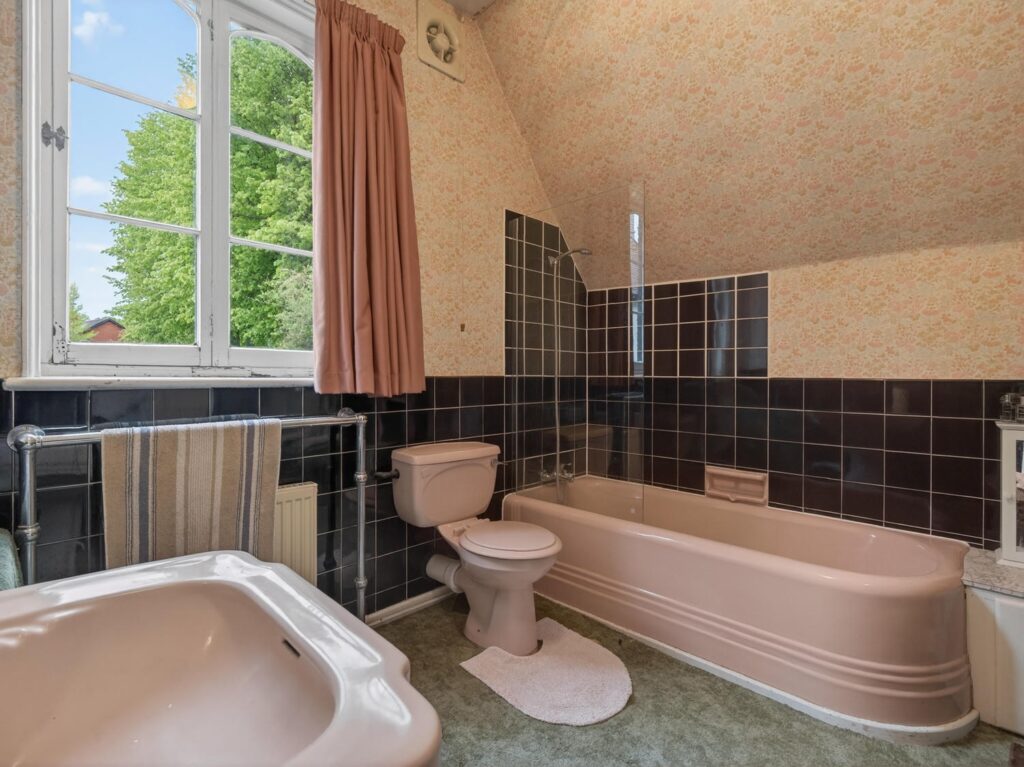 Family bathroom at The Priory Suffolk with arched window, pitched ceiling and three-piece suite