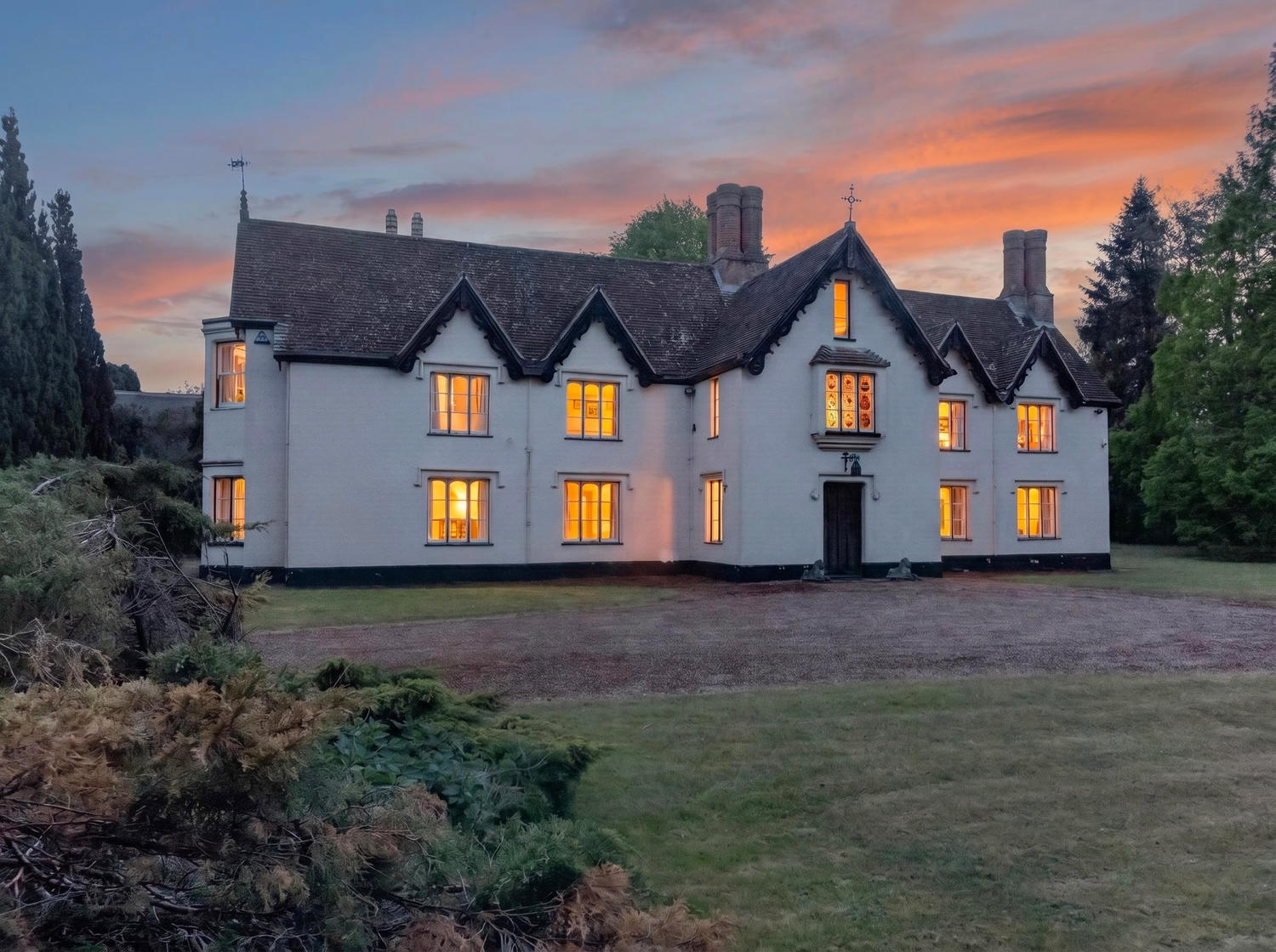 The Priory Suffolk front elevation at twilight with lit windows and sunset sky