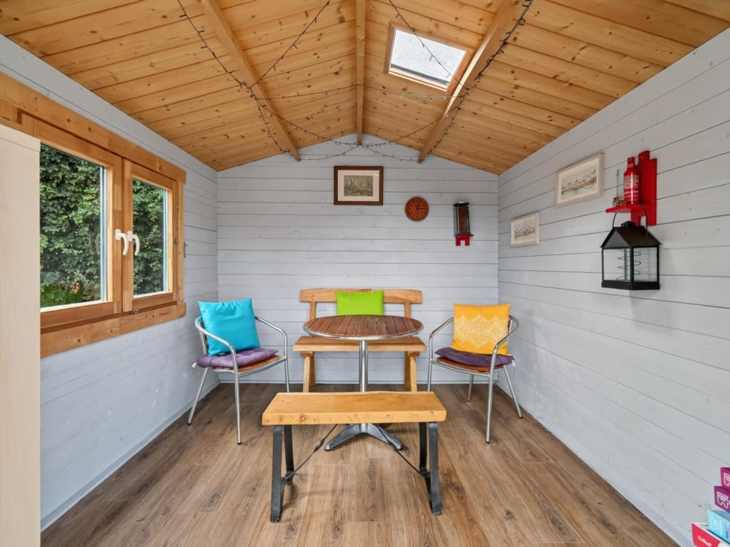 Garden room or summerhouse interior with pine apex ceiling, skylight, colourful cushioned seating and wooden table, The Tithe Barn, Sisland, Norfolk