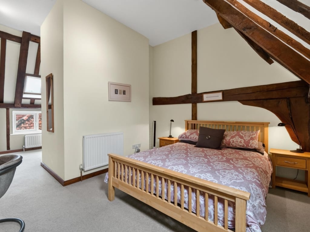 Bedroom with oak double bed, exposed timber frame beams, and rooflight window at The Tithe Barn, Sisland, Norfolk