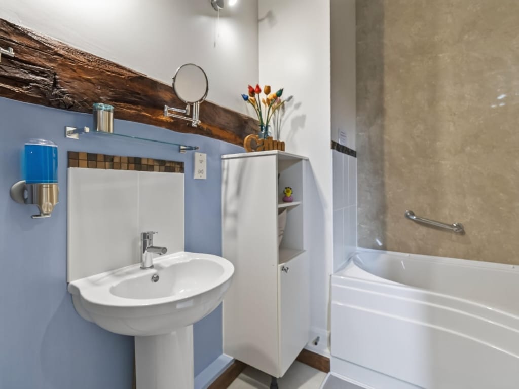 Bathroom with pedestal sink, bathtub, and exposed timber beam above mosaic tile splashback, The Tithe Barn, Sisland, Norfolk