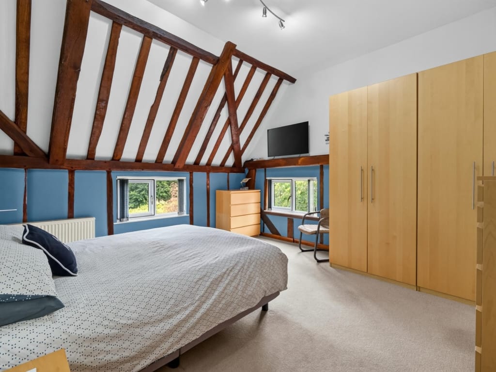 Bedroom with exposed timber frame trusses, double bed, fitted wardrobes and garden-view windows, The Tithe Barn, Sisland, Norfolk