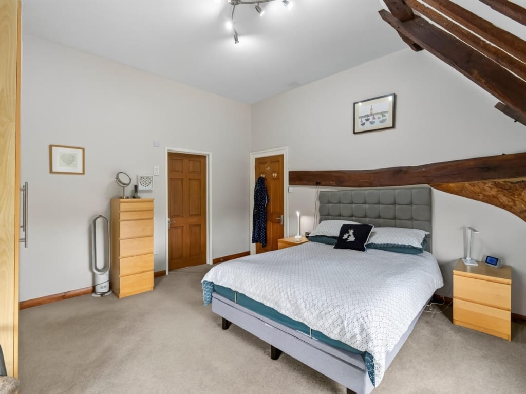 Bedroom with double bed, exposed timber beam, and fitted wardrobe at The Tithe Barn, Sisland, Norfolk