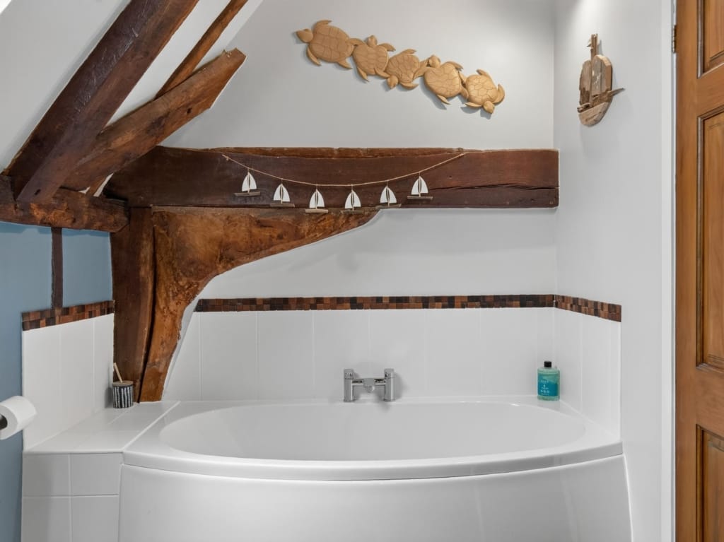 Family bathroom freestanding bath with exposed timber beams and mosaic tile border, The Tithe Barn, Sisland, Norfolk