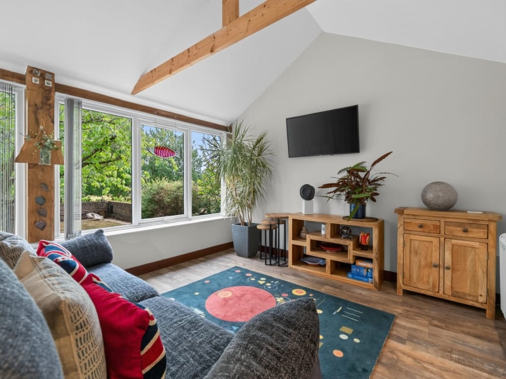 Sitting room with vaulted ceiling, exposed timber beams, wide garden-view window and oak furniture, The Tithe Barn, Sisland, Norfolk