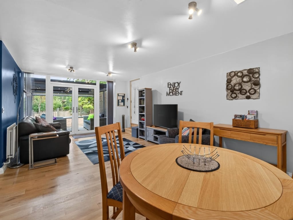 Open-plan living and dining room with oak round table, wood-effect floor, and French doors to garden, Owl Barn, Sisland, Norfolk