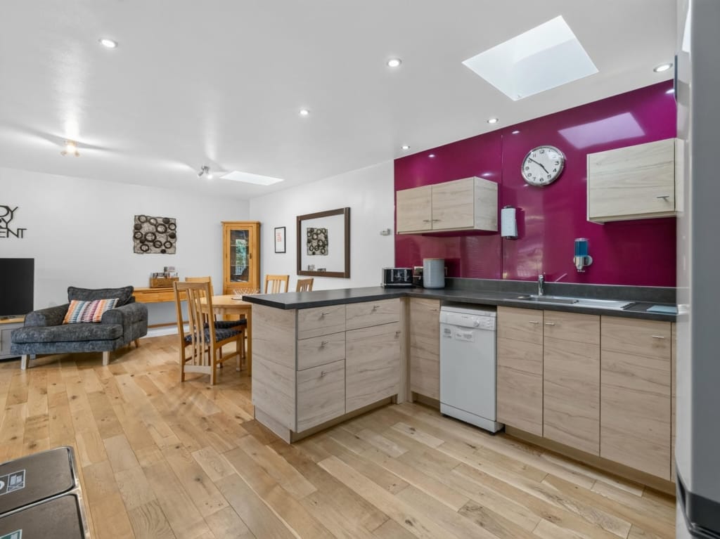 Owl Barn open-plan kitchen and living area with magenta splashback, oak-effect units, skylights, and pale wood flooring, Sisland, Norfolk