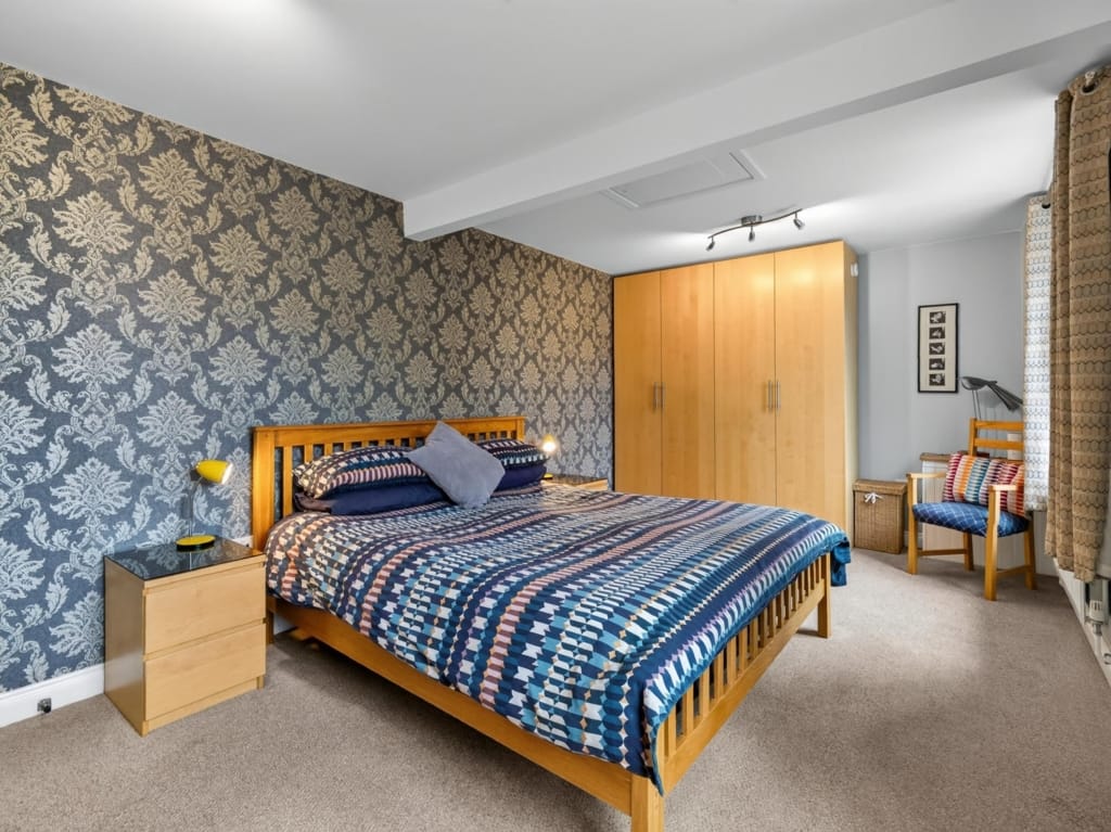 Bedroom with damask wallpaper, oak double bed, and fitted wardrobes at The Tithe Barn, Sisland, Norfolk