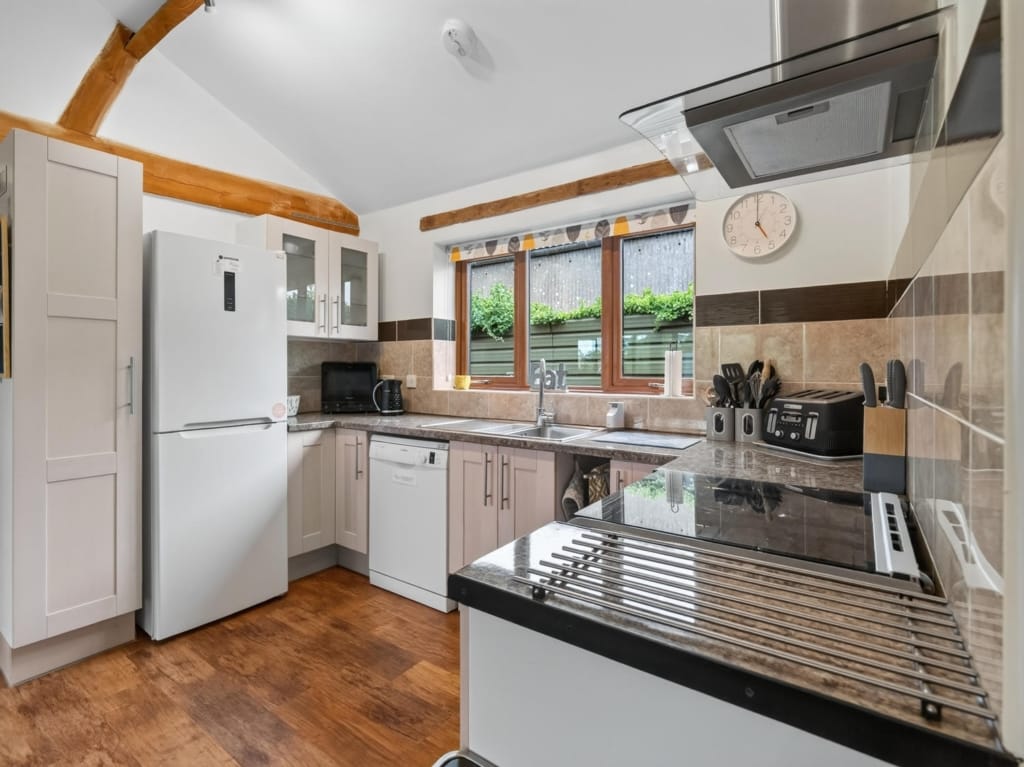 Holiday let kitchen with oak beams, fitted units, induction hob and garden-facing window, Owl Barn or Orchard Barn, Sisland, Norfolk