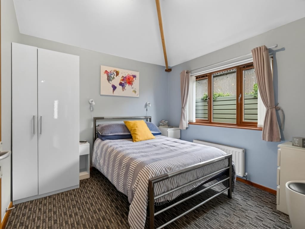 Bedroom in Owl Barn with metal-framed double bed, white wardrobe, and vaulted ceiling beam, Sisland Norfolk