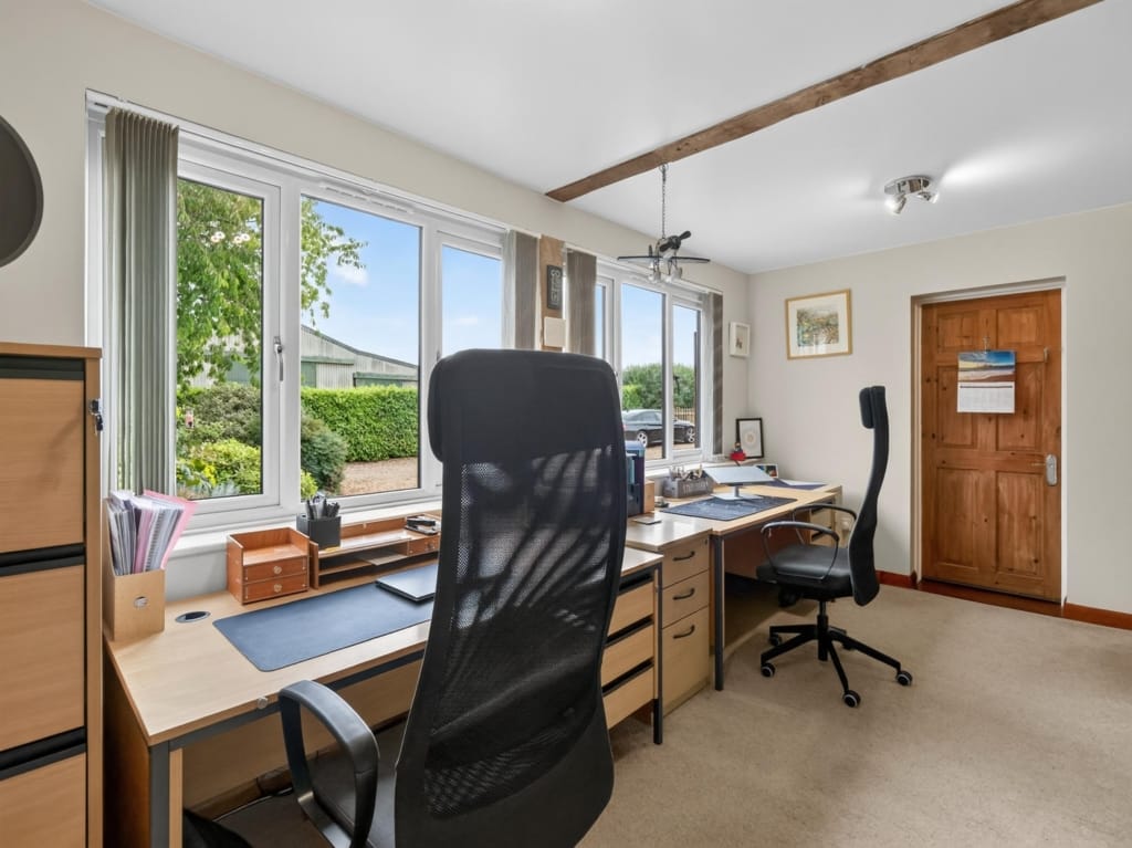 Study with two oak desks, exposed ceiling beam, and garden views at The Tithe Barn, Sisland, Norfolk