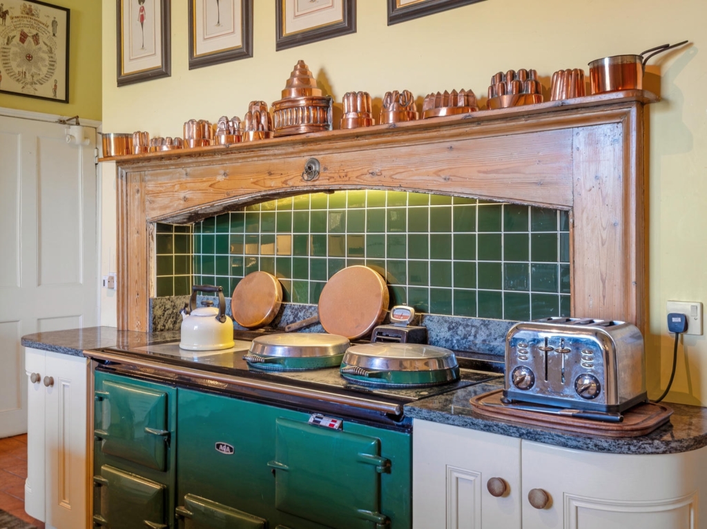 Green Aga set in a large timber chimney breast with copper moulds, Loddon Hall kitchen