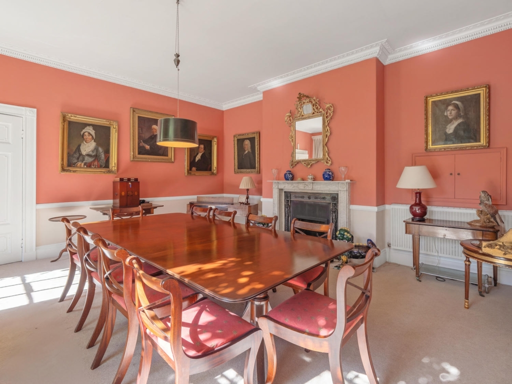 Formal dining room with period fireplace and portraits at Loddon Hall, Norfolk