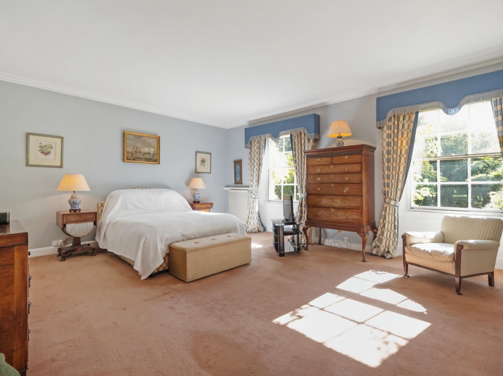Light double bedroom with two sash windows at Loddon Hall country house, Norfolk