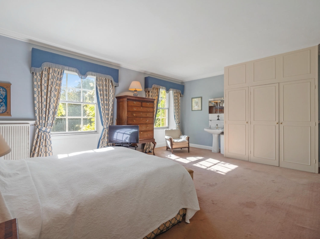 Spacious double bedroom with fitted wardrobes and basin at Loddon Hall, Norfolk