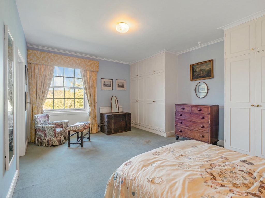 Bedroom with built-in wardrobes and sash window at Loddon Hall, Norfolk