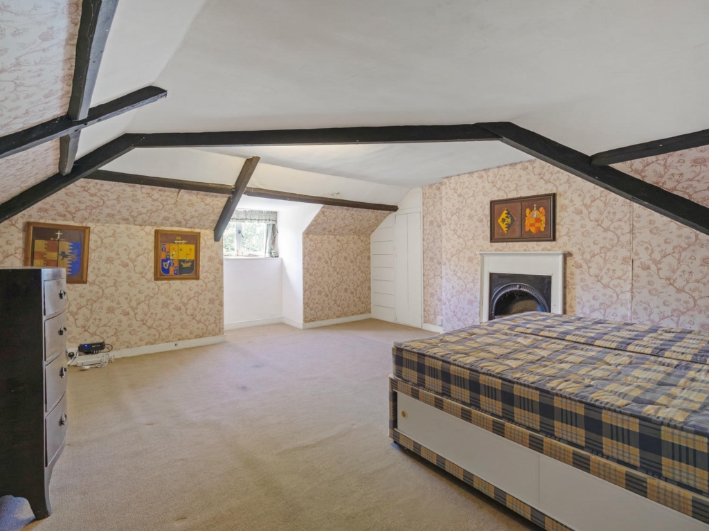 Second-floor bedroom with exposed beams and fireplace at Loddon Hall, Norfolk