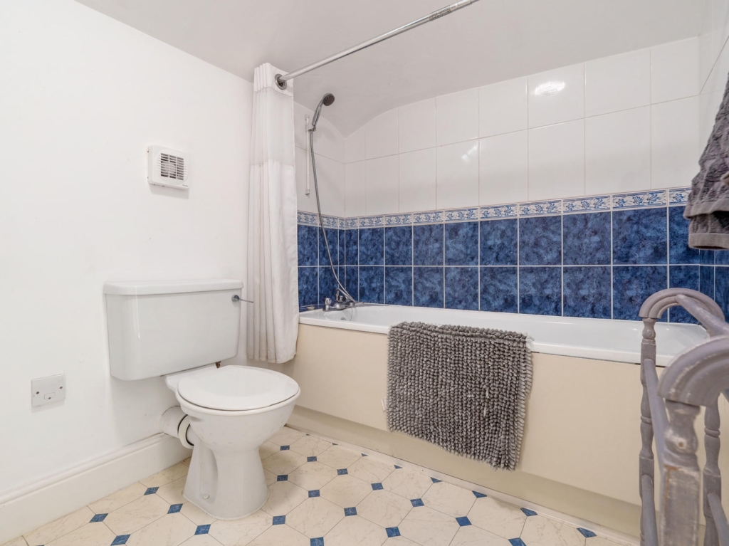 Bathroom with bath and tiling in Stable Cottage annexe at Loddon Hall, Norfolk