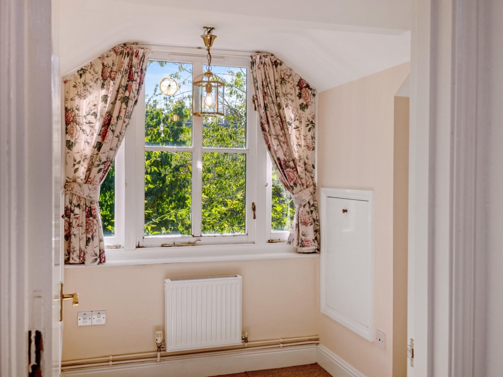 Window seat with floral curtains in Stable Cottage annexe at Loddon Hall