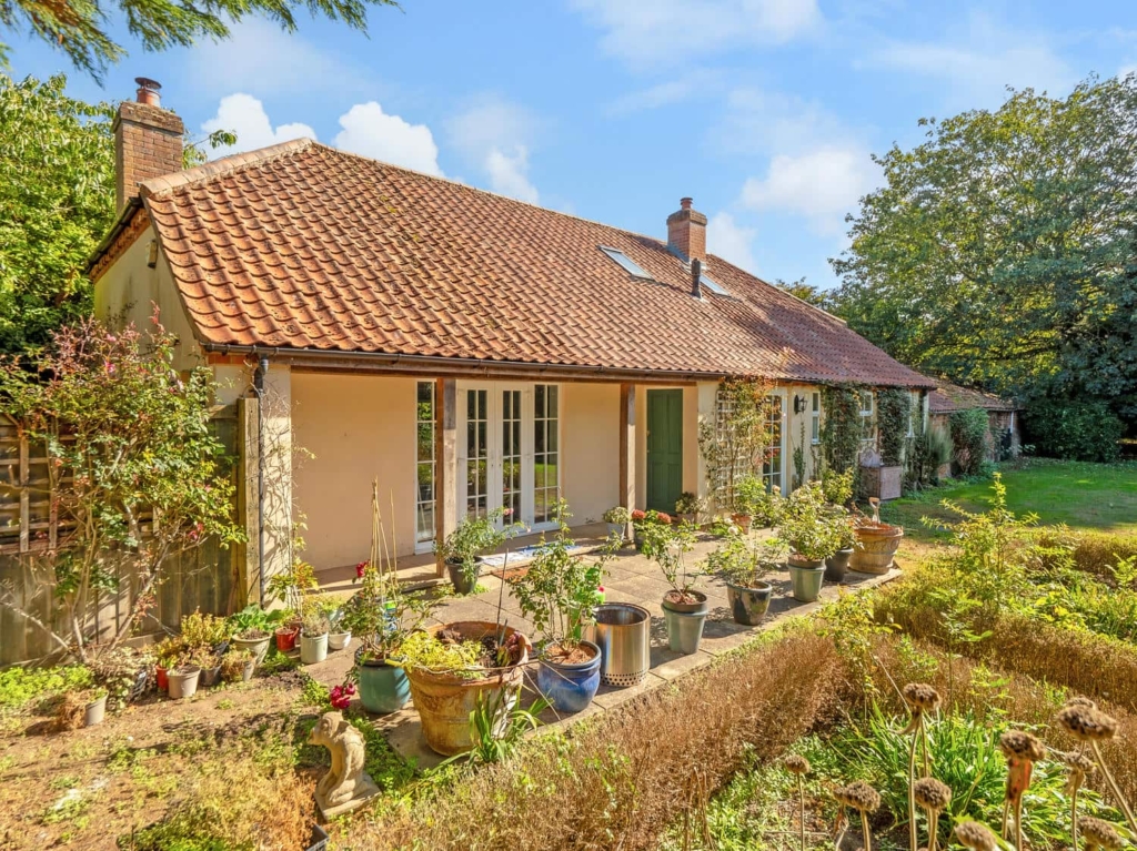Terrace with potted plants and French doors at Loddon Hall Cottage, Norfolk