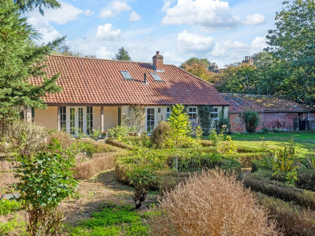 Loddon Hall Cottage and its gardens under a blue sky, Norfolk