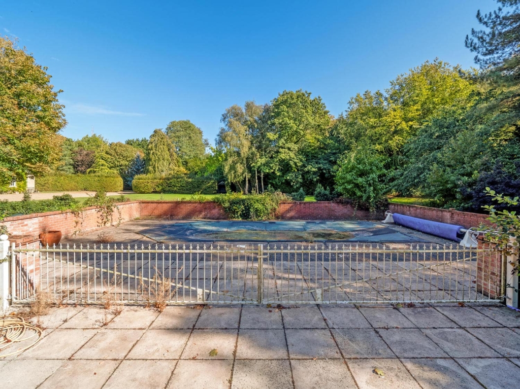 Walled swimming pool and paved terrace in the grounds of Loddon Hall, Norfolk