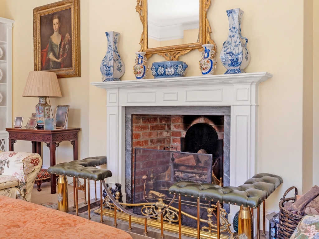 Period fireplace with white surround and mirror in the drawing room at Loddon Hall