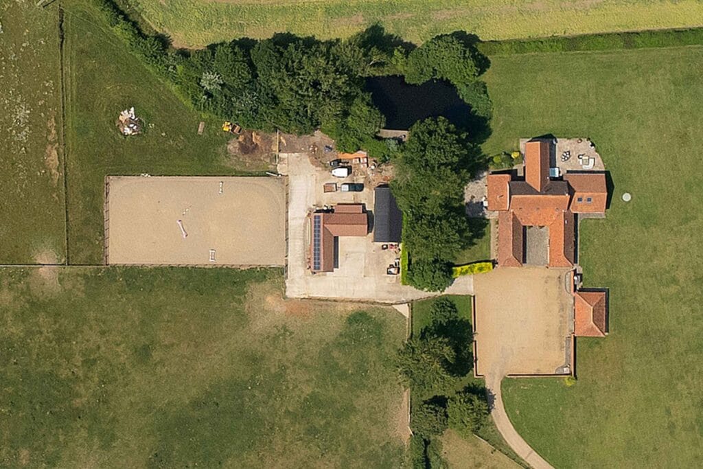 Aerial view of a premium equestrian property with stables, paddocks, and countryside setting in the UK