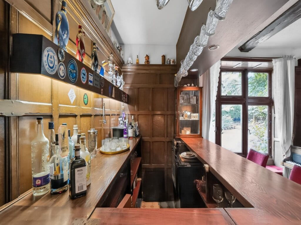 Elegant oak-panelled private bar with bottles and garden window view
